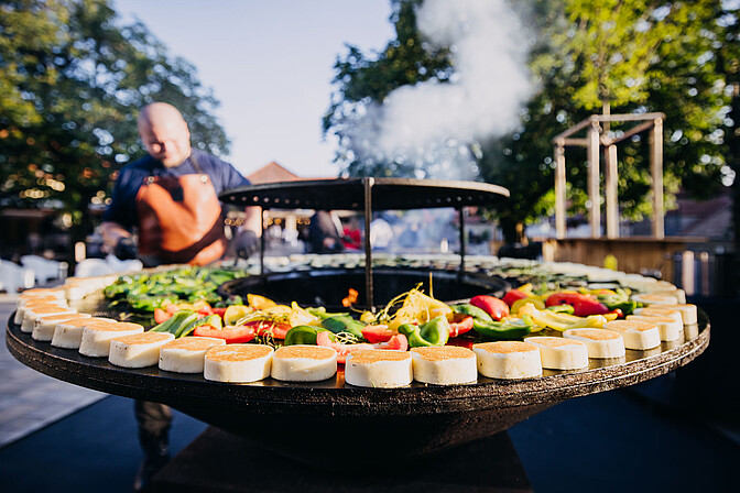 BBQ mit Gemüse auf einer Grilltonne im Innenhof der Eventlocation Gut Wöllried als Teil des Caterings eines Firmenevents