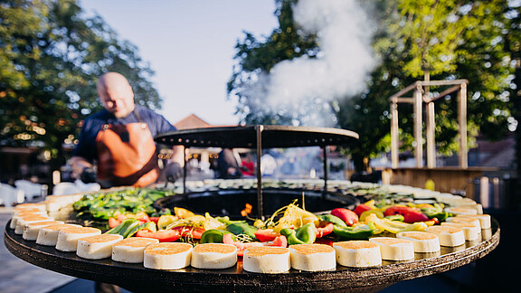BBQ mit Gemüse auf einer Grilltonne im Innenhof der Eventlocation Gut Wöllried als Teil des Caterings eines Firmenevents