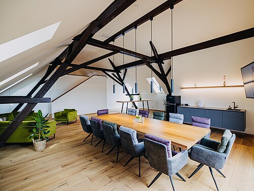 Modernes, helles Loft als Teil der Brennerei auf Gut Wöllried. Großer Tisch mit 12 Plätzen und Sitzecke mit Sofas