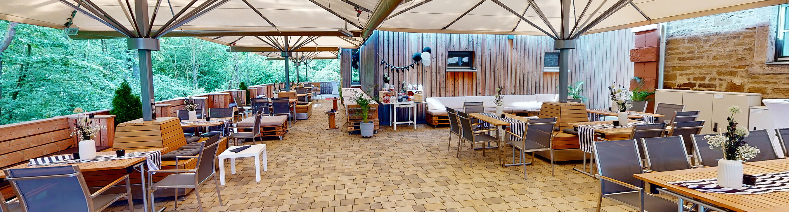 Vorbereiteter Außenbereich und Terrasse der Eventlocation Gut Wöllried mit direktem Blick ins Grüne auf viele Bäume.