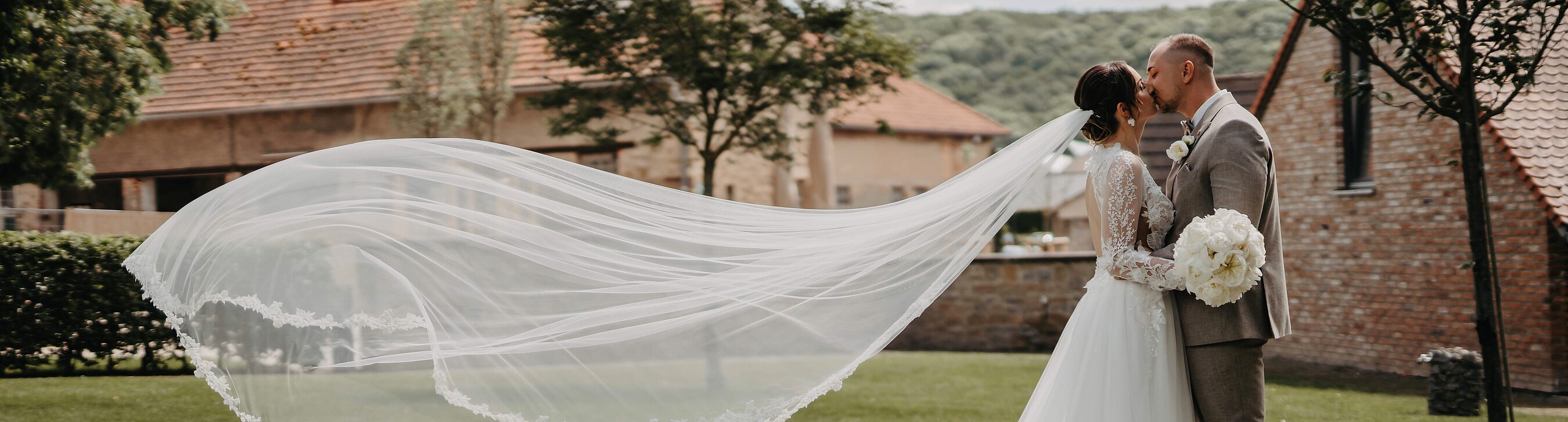 Hochzeitspaar küsst sich nach der Trauung im Gutsgarten der Hochzeitslocation Gut Wöllried bei sommerlichem Wetter